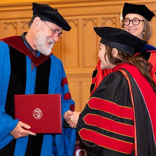 Theology graduate student receiving diploma at seminary graduation.